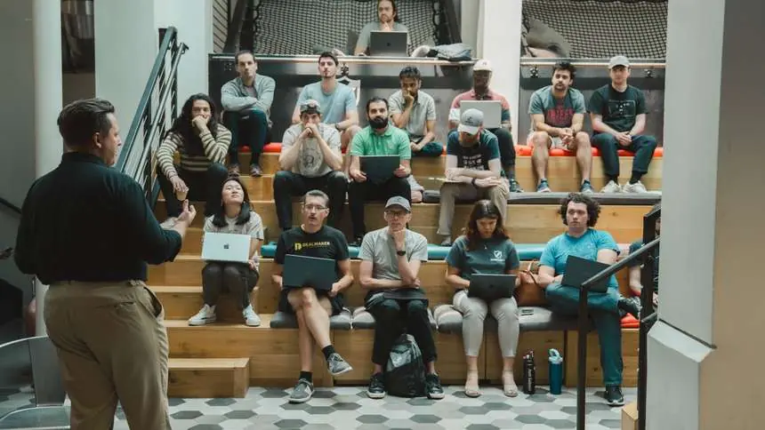 Live instruction in the atrium at Gauntlet HQ in Austin, Challengers seated on the bleachers with laptops