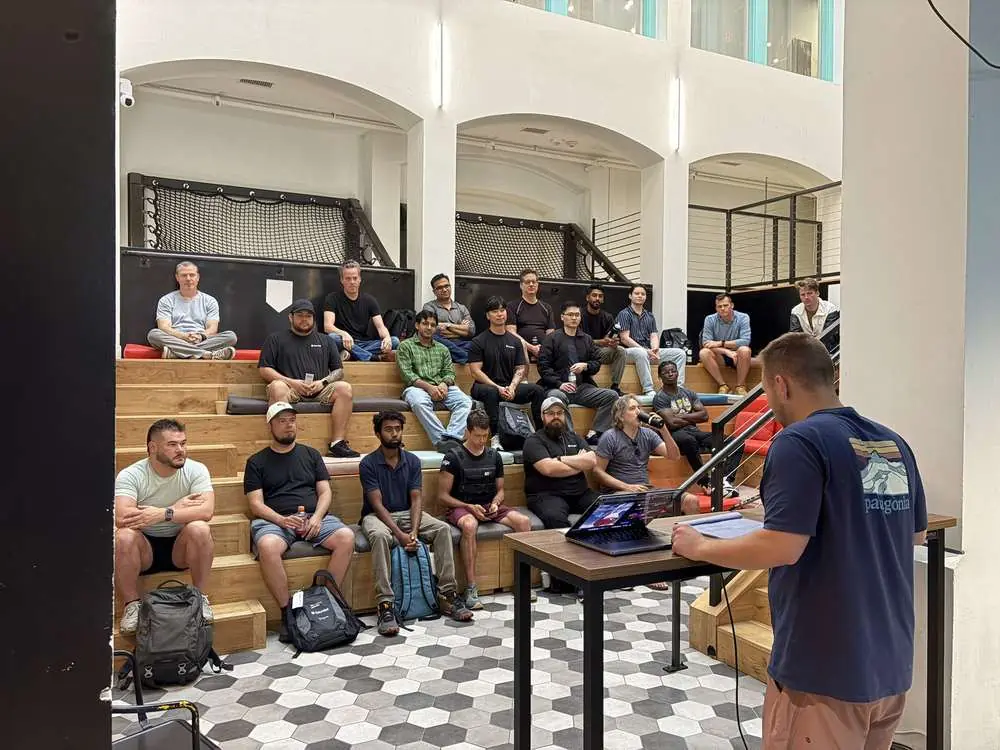 An instructor at a standing desk teaching Challengers on the atrium bleachers at Gauntlet HQ